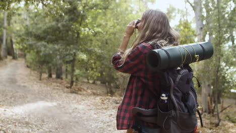 Young-backpacker-girl-with-camera-taking-pictures-of-forest