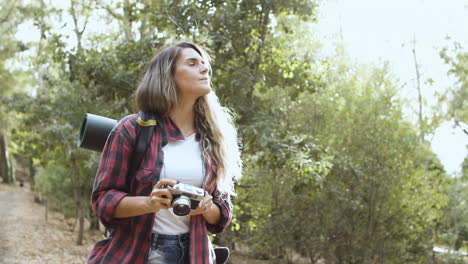 Inspired-backpacker-girl-with-camera-taking-pictures-of-forest