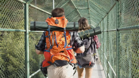 Couple-of-travelers-walking-on-bridge-above-steep