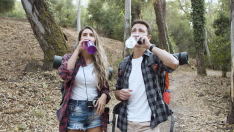 Couple-of-backpackers-drinking-fresh-water-and-talking-in-middle-of-the-woods