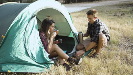Un-Par-De-Excursionistas-Bebiendo-Café-De-Un-Termo-En-El-Camping