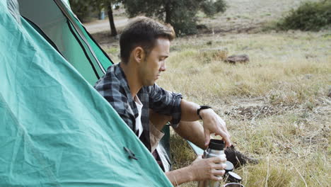 Serious-camping-guy-pouring-hot-drink-from-thermos-bottle