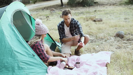 Camping-couple-eating-breakfast,-drinking-tea-or-coffee