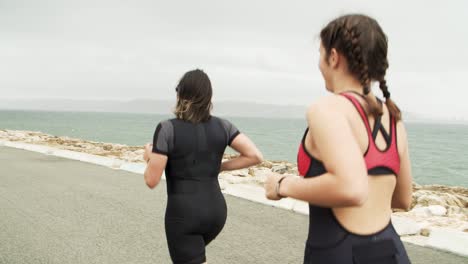 Rear-view-of-triathletes-training-for-marathon-near-the-sea