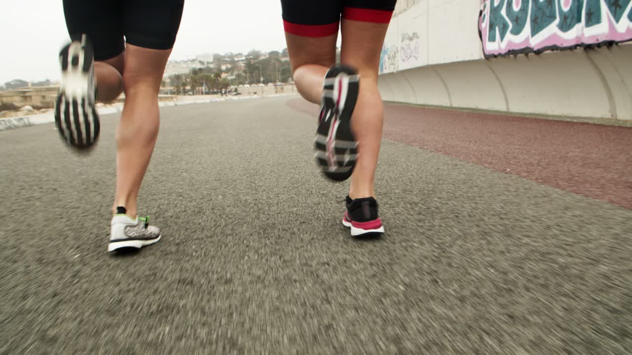 Free stock video Ankles and feet of runners jogging along road