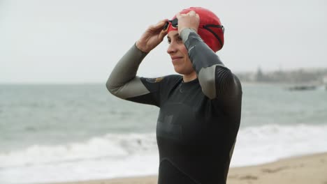 Young-woman-in-wetsuit-wearing-goggles-and-warming-up