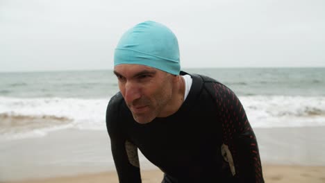 Tired-male-swimmer-standing-on-beach