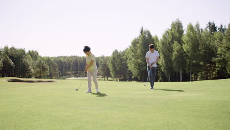 Asian-couple-practicing-golf-on-grass-field