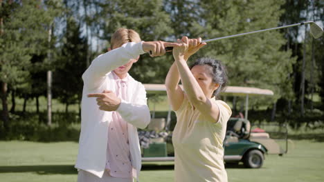 Golf-teacher-helping-asian-mature-woman-with-the-golf-postures