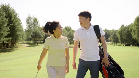 Asiatische-Paar-Reden,-Während-Sie-Den-Golfplatz-überqueren