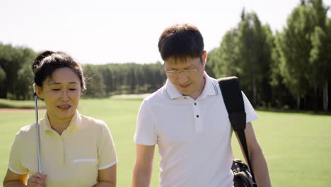 Couple-talking-in-middle-of-golf-practicing