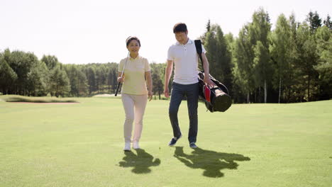 Golf-players-walking-and-talking-on-grass-field