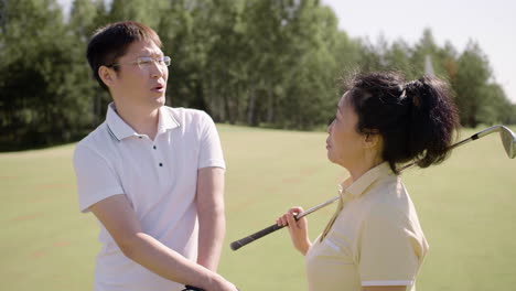 Asiatische-Golfspieler,-Die-Sich-Auf-Dem-Grasfeld-Unterhalten