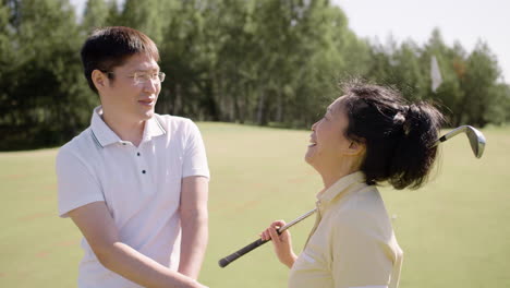 Happy-man-and-woman-talking-on-golf-field