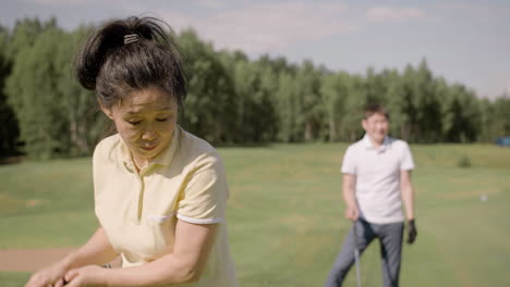Asian-man-and-woman-talking-and-playing-golf-on-sunny-day