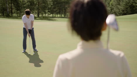 Asian-man-with-glasses-playing-golf-and-celebrating-with-his-wife