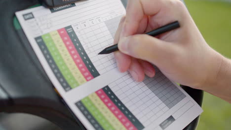 Golf-player-writing-the-marks-of-the-golf-competition-on-paper