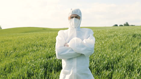 Caucasian-researcher-man-in-white-protective-suit-and-goggles-doing-pest-control-in-the-green-field