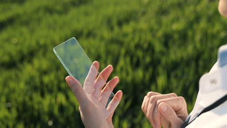 Close-up-view-of-researcher-woman-hands-in-gloves-tapping-on-glass-in-the-green-field