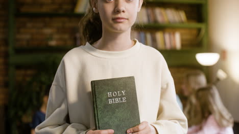 Closeup-of-smiling-girl-in-class,-holding-the-Bible