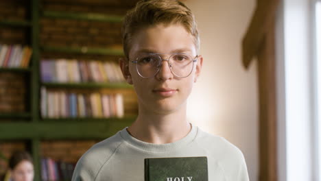 Medium-shot-of-blond-student-showing-Bible-book