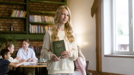 Young-girl-showing-Bible-book-at-the-school