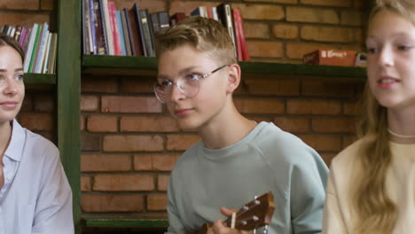 Closeup-blond-student-playing-the-ukelele-for-his-class