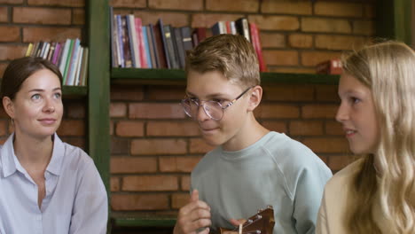 Young-blond-kid-in-glasses-playing-the-ukelele-for-his-teacher-and-classmates