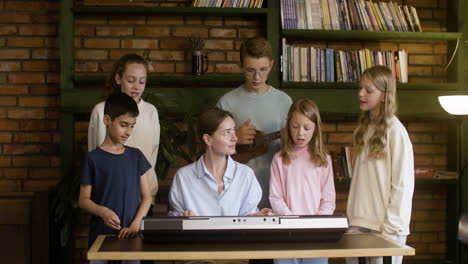 Lehrer-Spielt-Keyboard,-Blondes-Kind-Spielt-Ukulele-Und-Der-Rest-Der-Schüler-Singt