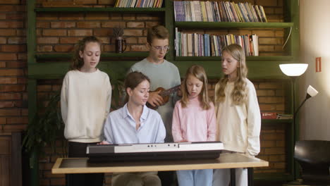 Profesor-Y-Niños-Cantando-Y-Tocando-Música-En-La-Escuela