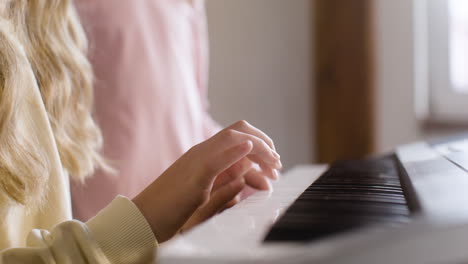 Closeup-of-blond-girl-playing-piano-keyboard-at-school