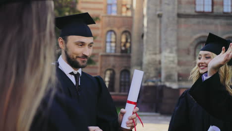 Graduados-Caucásicos-Masculinos-Y-Femeninos-Con-Sus-Diplomas-Y-Hablando-Después-Del-Día-De-Graduación-En-El-Edificio-De-Su-Universidad