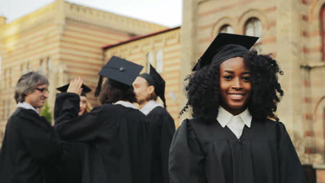 Retrato-De-La-Joven-Graduada-Afroamericana-Sonriente-Posando-Para-La-Cámara-Y-Sonriendo-Frente-A-La-Universidad