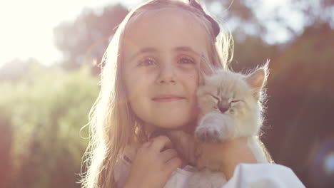 Portrait-of-a-little-blonde-girl-holding-kitty-cat-and-smiling-in-the-sunlight