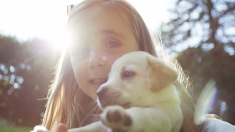 Close-up-view-of-teh-small-lovely-girl-holding-her-labrador-puppy-in-the-park-on-a-sunny-day