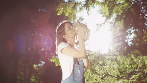 Young-Caucasian-woman-in-glasses-holding-small-cat-and-kissing-it-in-the-park-on-a-summer-day