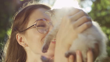 Nahaufnahme-Einer-Kaukasischen-Frau-Mit-Brille,-Die-Eine-Kleine-Katze-Hält-Und-Sie-An-Einem-Sommertag-Im-Park-Küsst