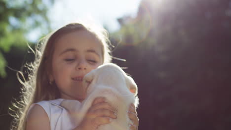 Close-up-view-of-a-caucasian-little-girl-spinning-around-while-holding-a-small-labrador-puppy-and-playing-with-it-in-the-park-on-a-summer-day