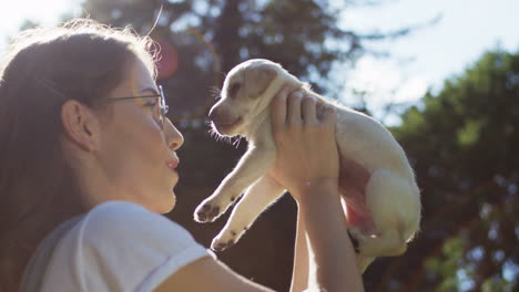 Caucasian-young-woman-in-glasses-holding-a-labrador-puppy-in-the-park-on-a-summer-day