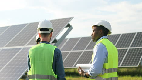 Three-multiethnics-farm-solar-engineers-talking-on-solar-plantation