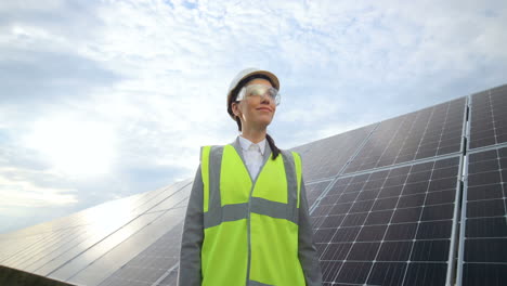 Bottom-view-of-young-caucasian-woman-engineer-in-white-helmet-and-goggles-on-solar-panel