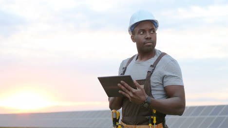 Junger-Afroamerikanischer-Männlicher-Ingenieur,-Der-Ein-Tablet-Auf-Einer-Solarplantage-Verwendet