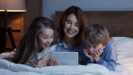 Caucasian-mother-and-his-little-son-and-daughter-lying-on-the-bed-and-watching-something-on-the-tablet