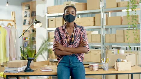 Diseñadora-Afroamericana-Con-Máscara-Negra-Mirando-La-Cámara-De-Buen-Humor-En-La-Tienda-De-Ropa