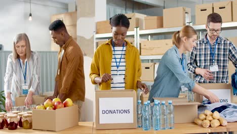 Multiethnic-group-of-volunteers-packing-boxes-with-food-and-clothes-in-charity-warehouse