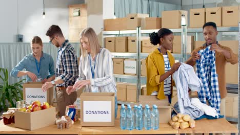 Multiethnic-group-of-volunteers-packing-boxes-with-food-and-clothes-in-charity-warehouse