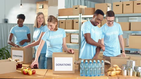 Multiethnische-Gruppe-Von-Freiwilligen,-Die-Kisten-Mit-Lebensmitteln-Und-Kleidung-In-Einem-Wohltätigkeitslager-Arbeiten-Und-Packen