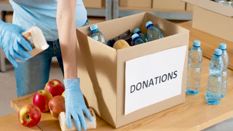 Nahaufnahme-Der-Freiwilligen-Hände-Verpackungsbox-Mit-Lebensmitteln-Und-Wasser-Im-Wohltätigkeitslager