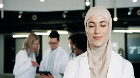 Close-up-view-of-arabic-female-doctor-wearing-hijab-and-looking-at-camera-standing-in-hospital