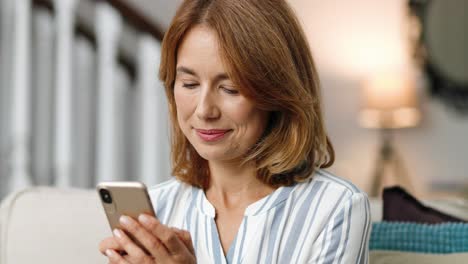 Close-up-portrait-of-cheerful-woman-in-good-mood-typing-on-smartphone